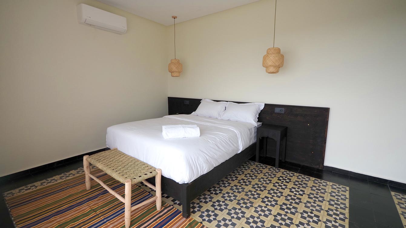 Chambre double avec lit en bois sculpté et tapis berbère à Taghazout, tête de lit berbère