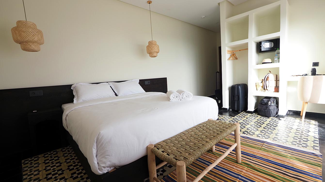 Chambre double avec lit en bois sculpté et tapis berbère à Taghazout, tête de lit berbère