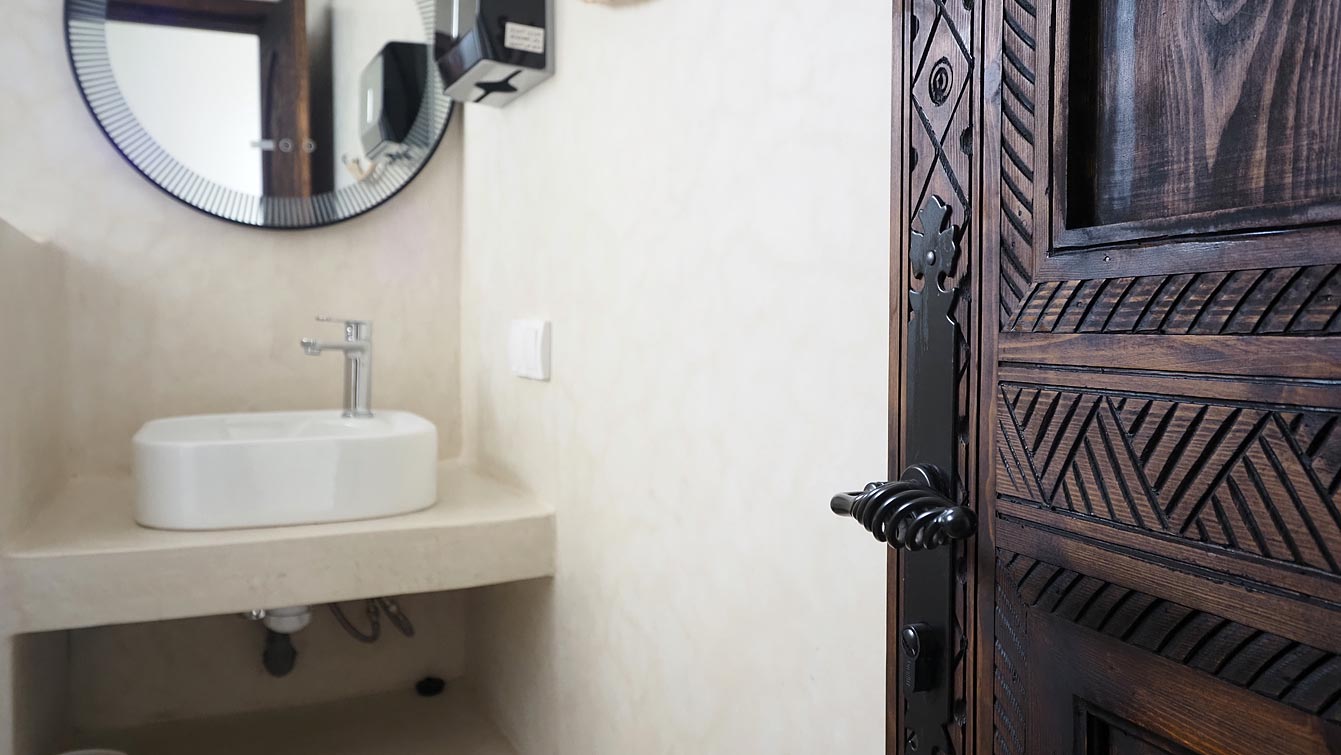 Salle de bain en tadelakt avec vasque et miroir rond au Sea & Sunset Villa