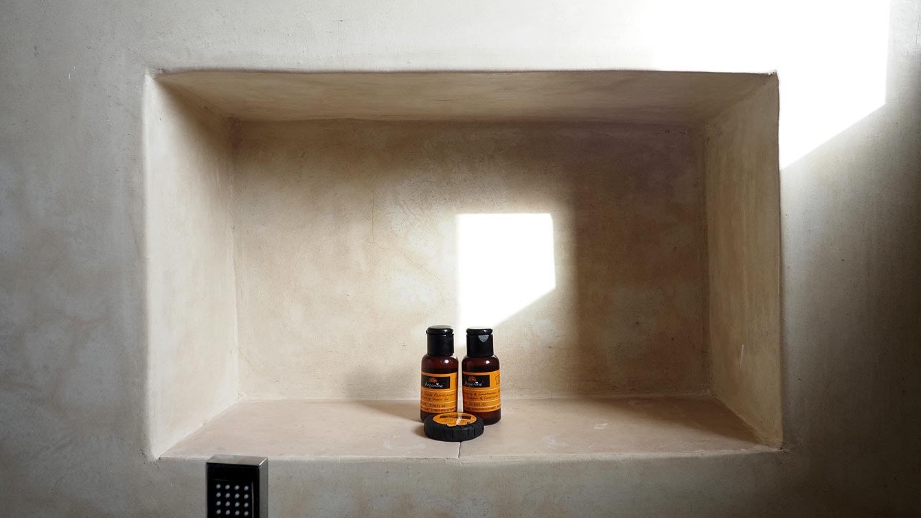 Produits à l'argan dans une niche en tadelakt de la salle de bain