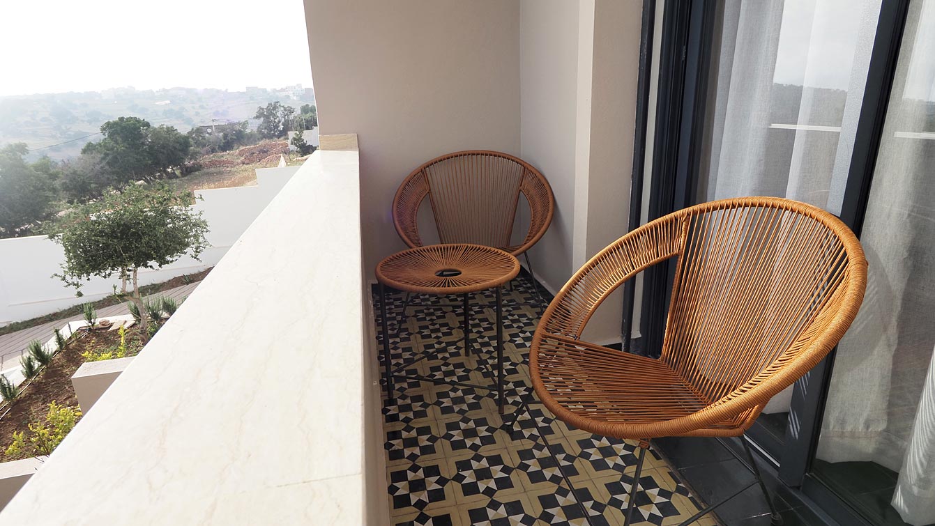 Balcon avec fauteuils en cordage et vue sur les collines de Taghazout