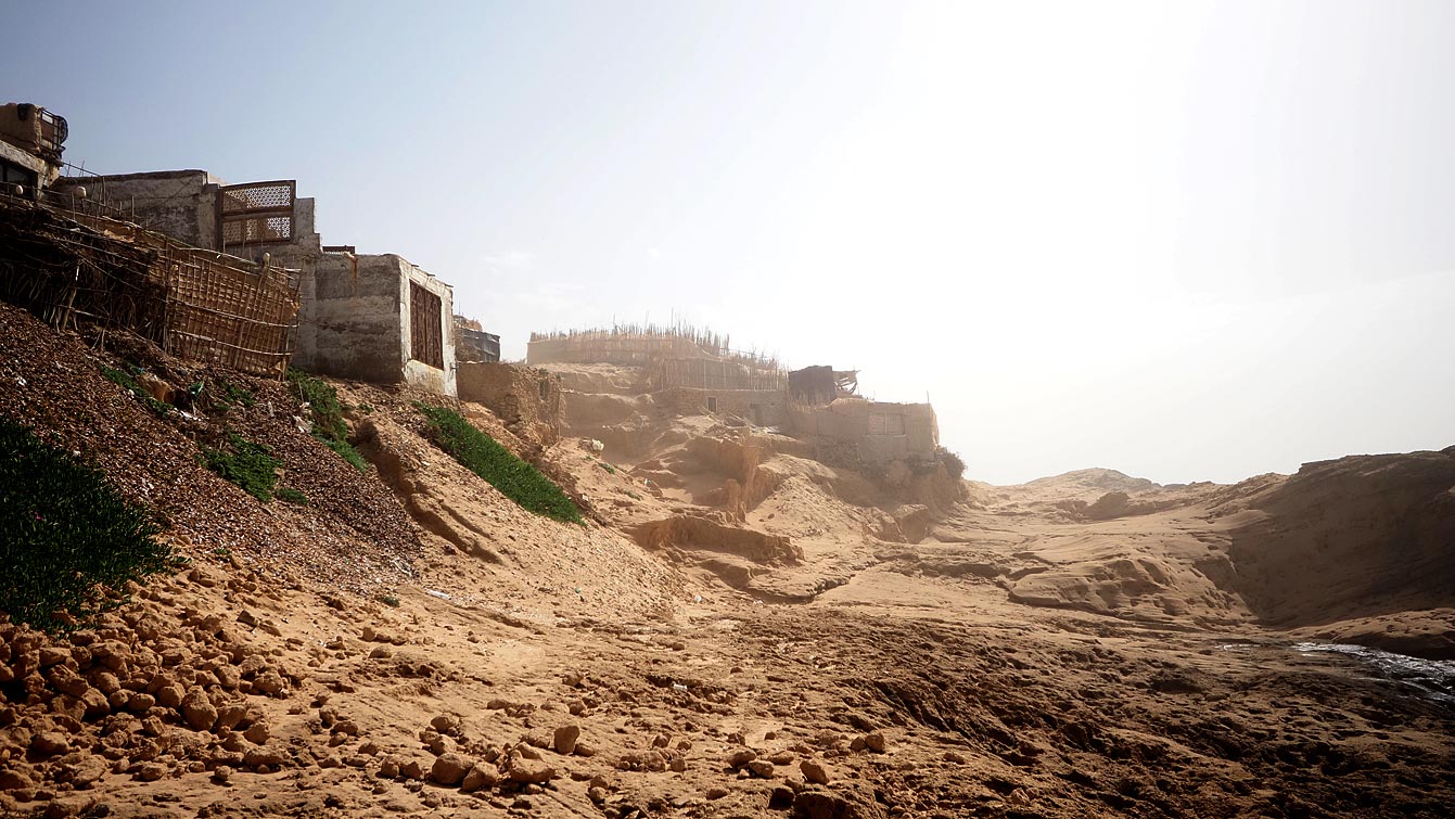 Cabanes du village de pêcheurs surplombant une plage aux dunes de Timlalin.